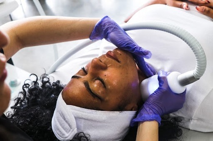 A woman receiving a cryo-facial treatment in a spa