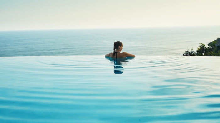 Luxury Resort. Woman Relaxing In Pool. Summer Travel Vacation