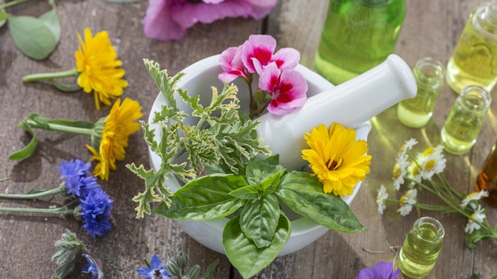 fresh herbs and flowers in a mortar for making essential oils and aromatherapy