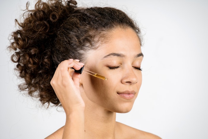 woman holding dropper with serum oil near fresh perfect skin