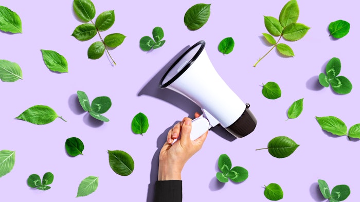 Person holding a megaphone with green leaves - flat lay